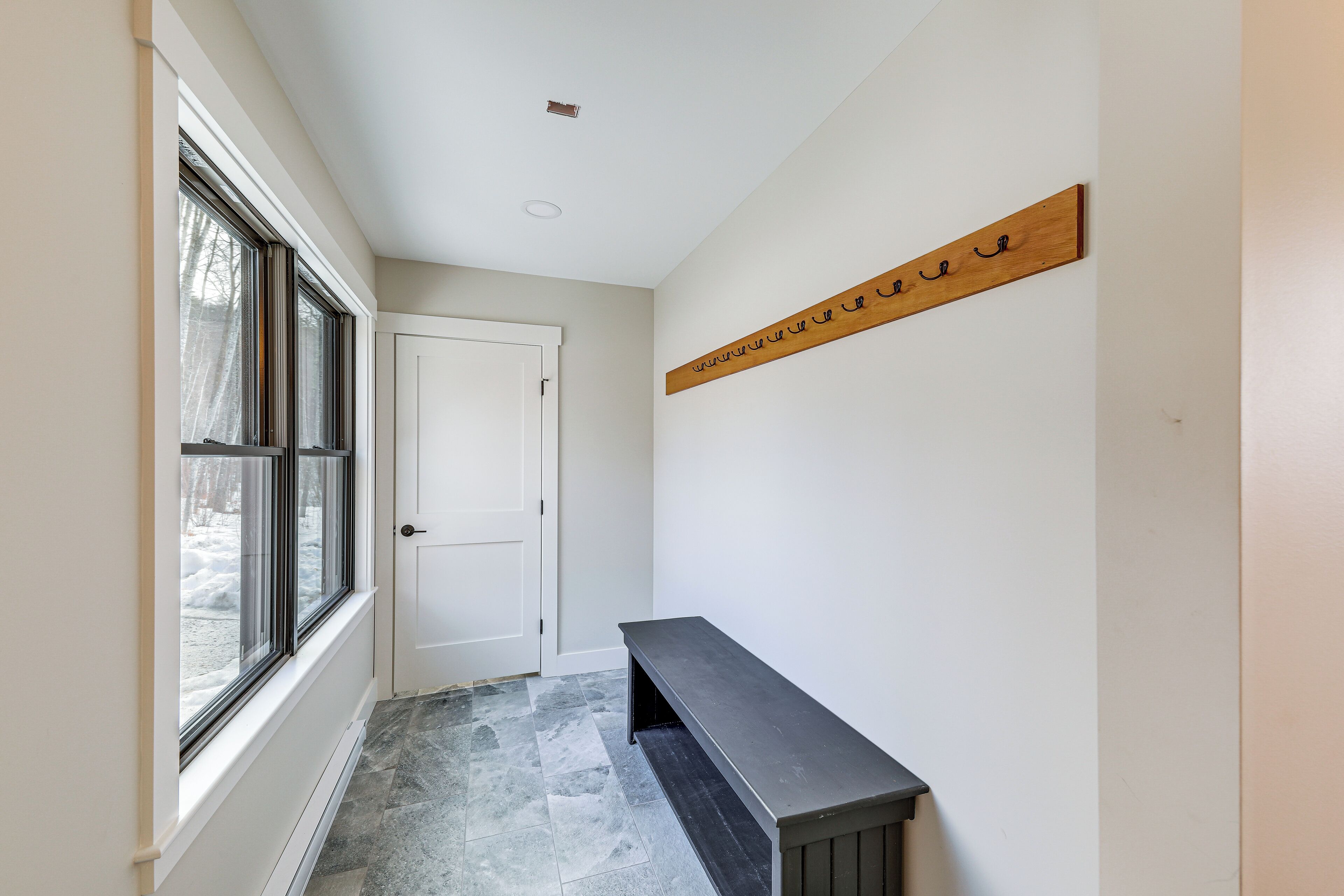 A hallway with a bench, a door, and a wall-mounted sign.