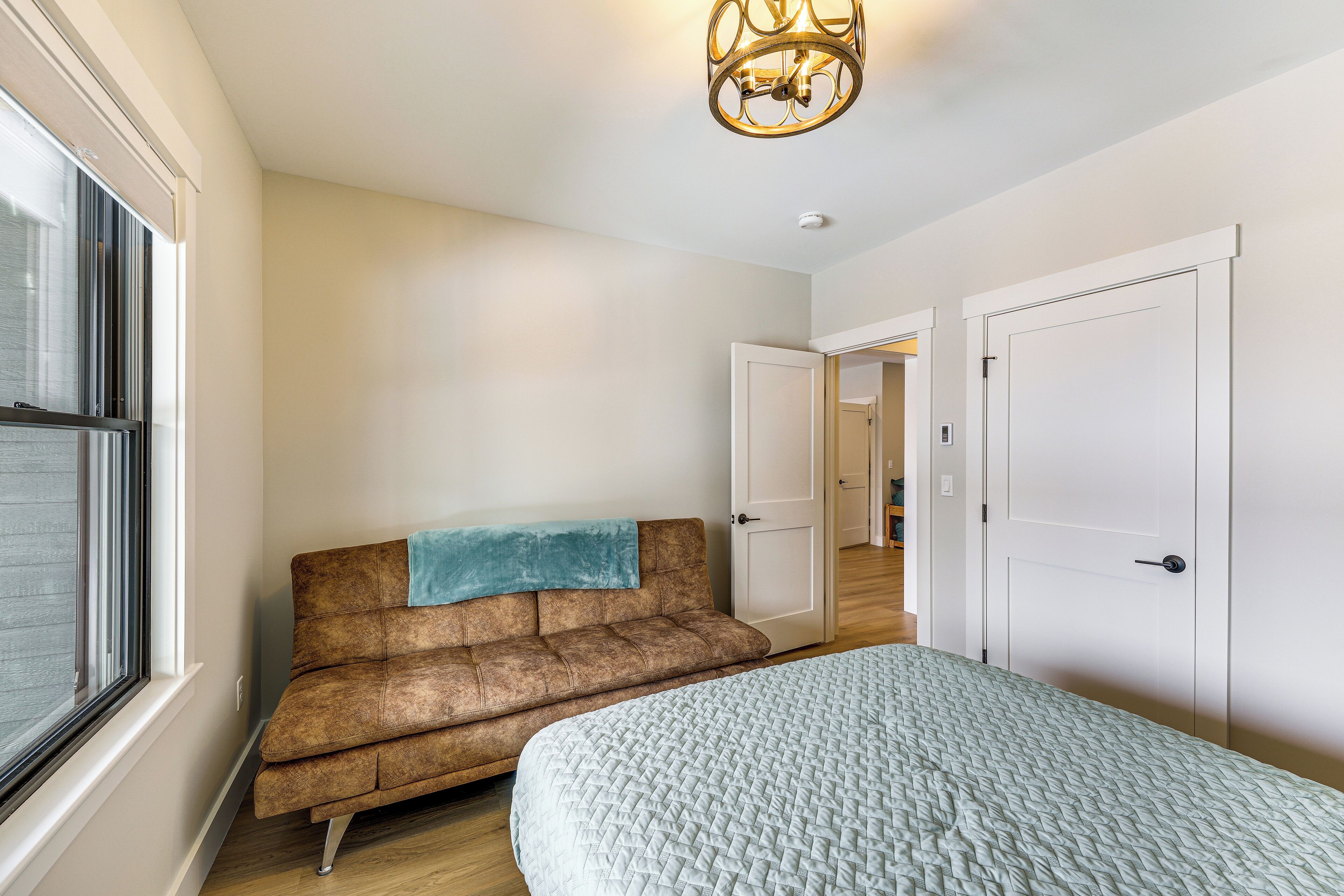 Une chambre à coucher avec un lit, un canapé marron et une fenêtre.