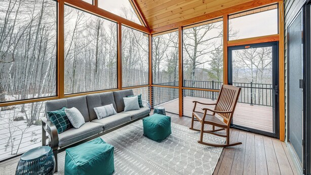 A cozy, well-lit room with a wooden ceiling and large windows offering a view of a snowy landscape. - Mountain-view Home in Stoneham w/ Hot Yoga Studio! (Lovell)