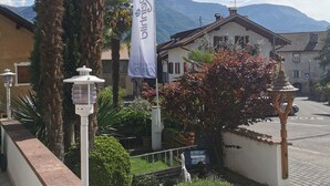 A courtyard with a flag, a street lamp, and a flower bed. - Appartment "laugen" (Nals)