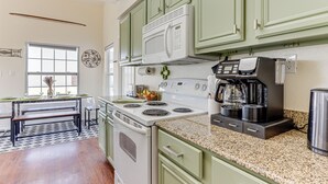 A kitchen with green cabinets, a white stove, and a coffee maker. - Game Room, Hot Tub & Grill: Afton Retreat! (Afton)