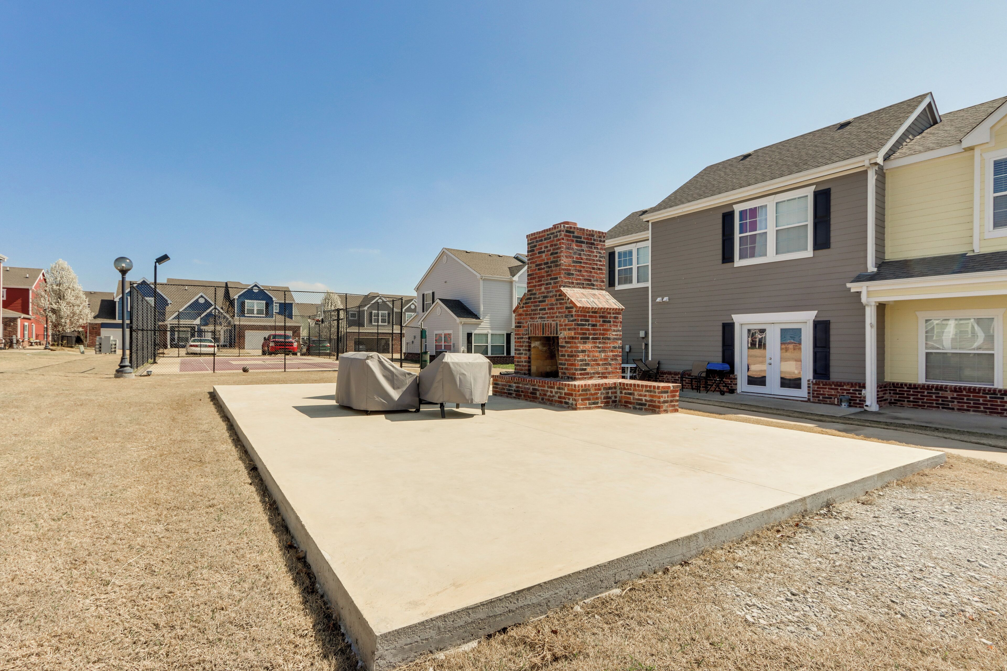 Zona residencial con casas, una parrilla y mobiliario exterior.