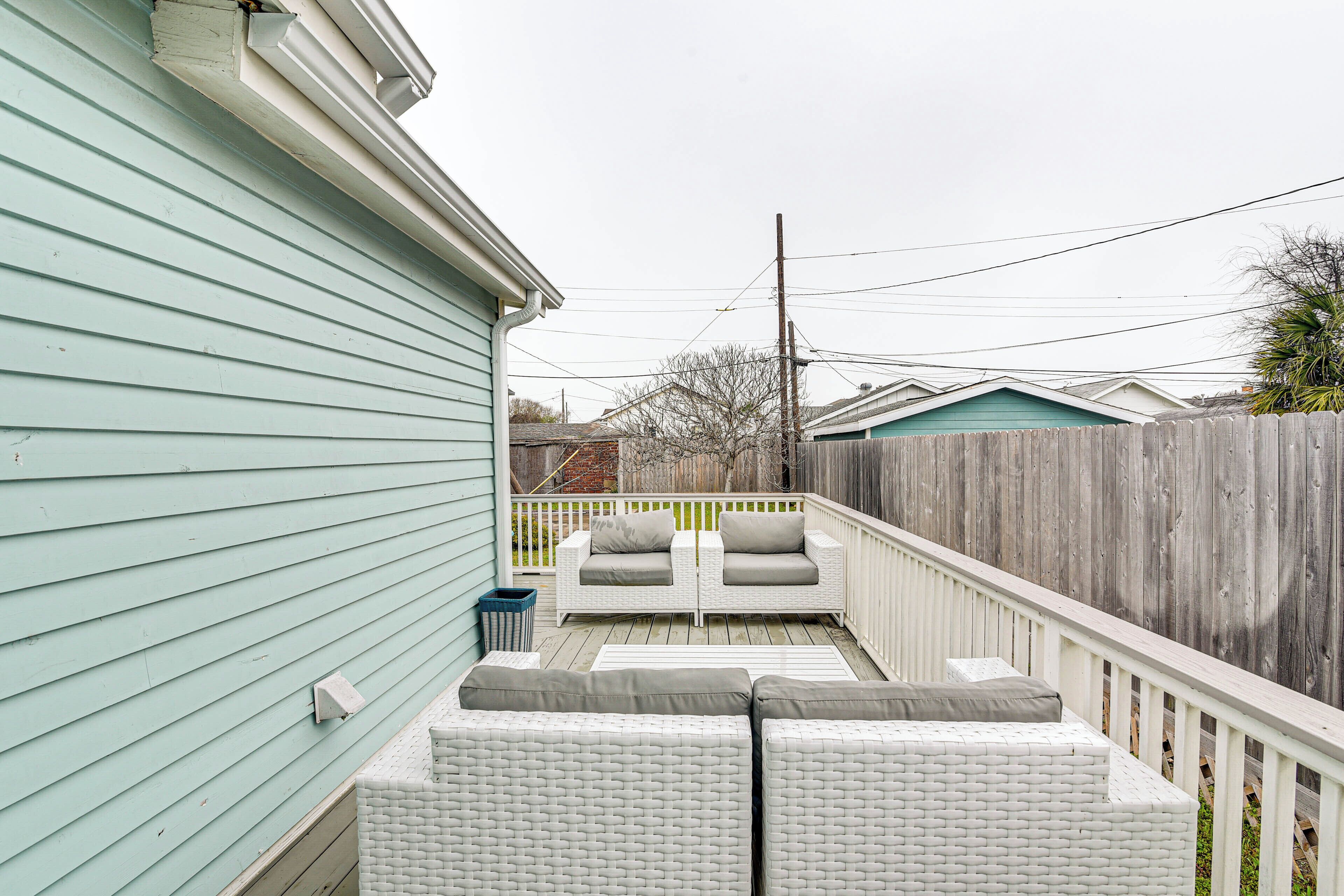 A covered patio with white wicker furniture and a wooden deck.