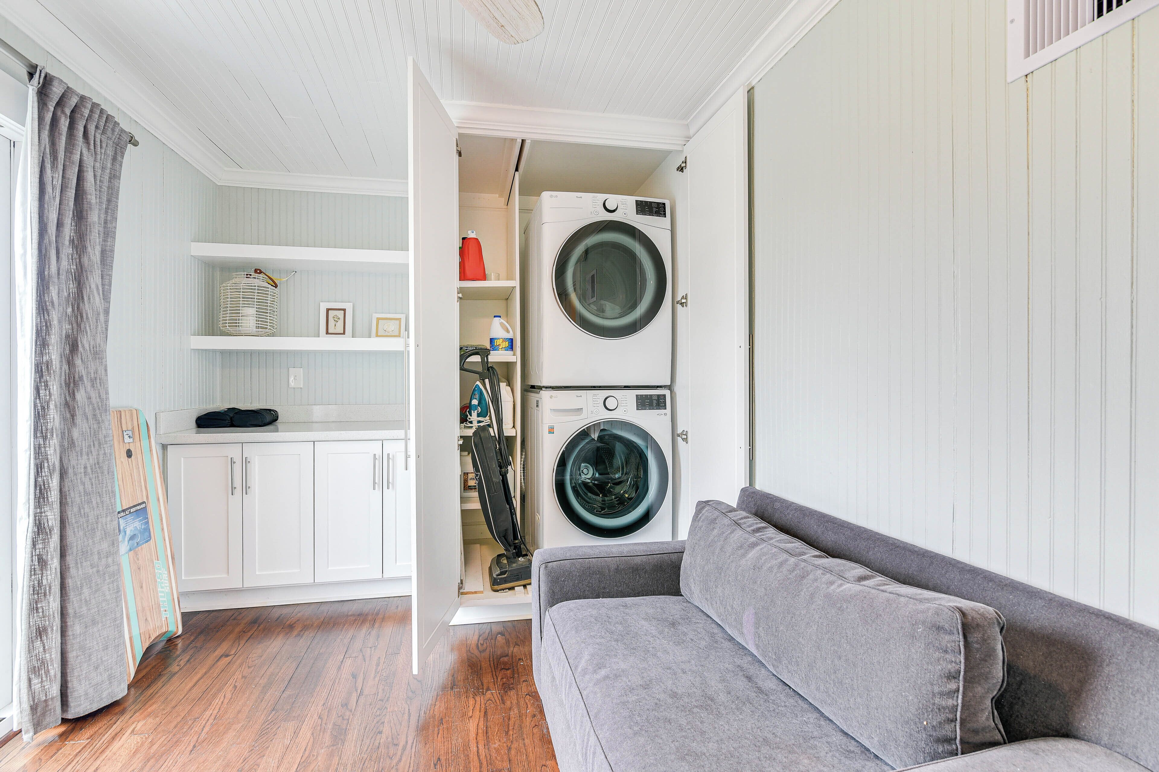A compact living space with a grey sofa, a washing machine, and a white cabinet.