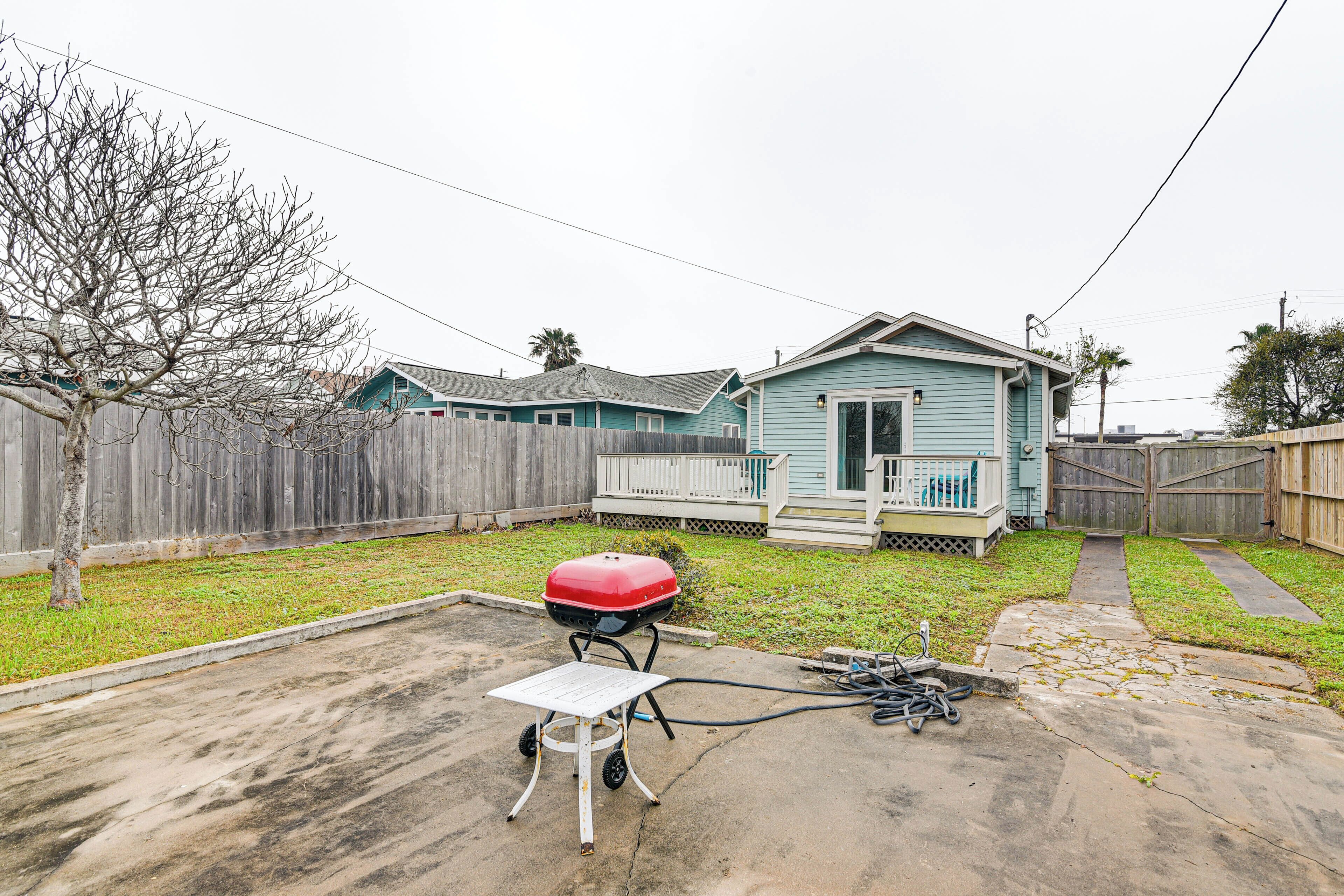 A backyard with a barbecue grill, a wooden fence, and a house with a porch.
