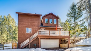 A two-story wooden house with a balcony, a garage, and a staircase leading to the upper level. - Woodland Park Chalet w/ Deck, Grill & Mtn Views! (Woodland Park)