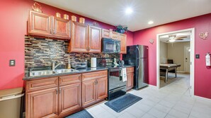 A kitchen with wooden cabinets, a black countertop, a tiled backsplash, and a stainless steel refrigerator. - Pool Table & Patio: Cozy Lawrenceville Apt (Lawrenceville)