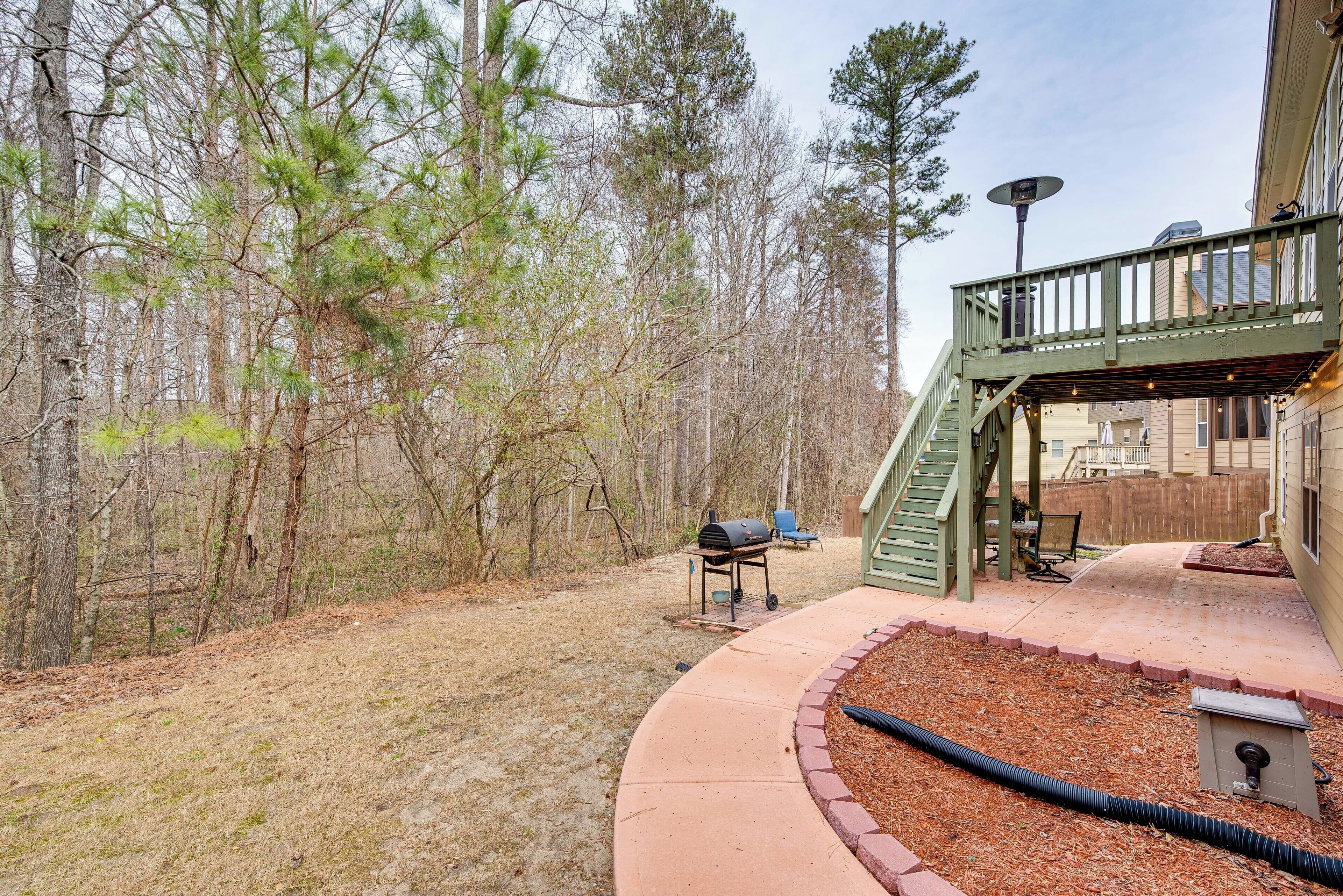 A backyard with a wooden deck, a grill, and a covered seating area.