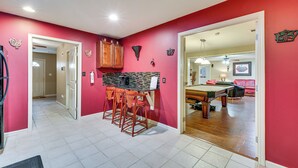 A kitchen with a bar area, wooden cabinets, and a tiled floor. - Pool Table & Patio: Cozy Lawrenceville Apt (Lawrenceville)