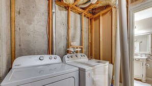 A laundry room with two Whirlpool washers and dryers, exposed wooden beams, and a view into a bathroom with a sink and mirror. - Pool Table & Patio: Cozy Lawrenceville Apt (Lawrenceville)