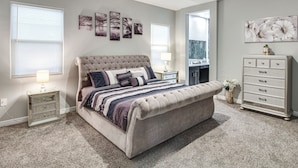 Een slaapkamer met een groot bed, nachtkastjes, een kaptafel en kunst aan de wanden.