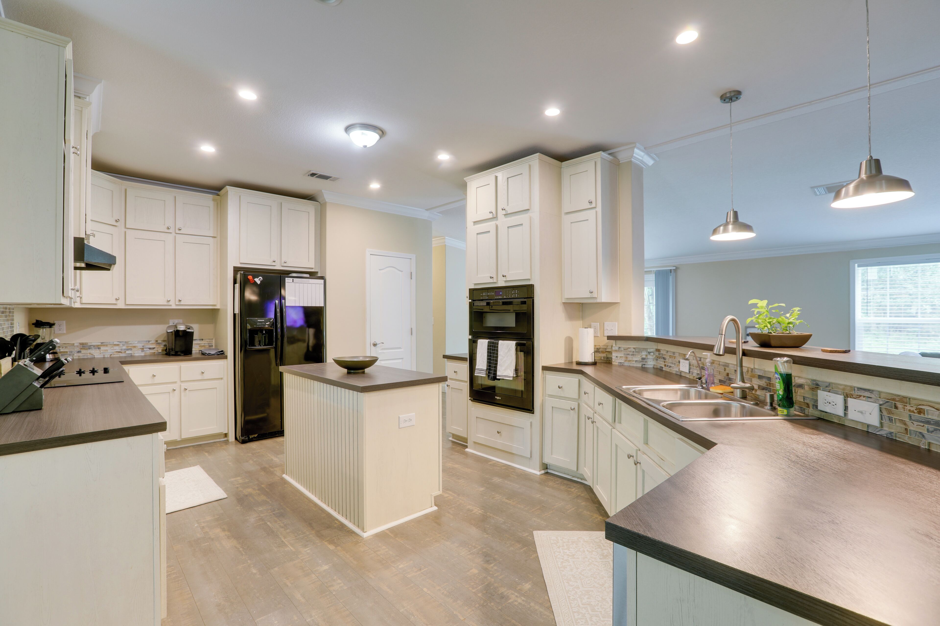A modern kitchen with white cabinetry, stainless steel appliances, and pendant lighting.