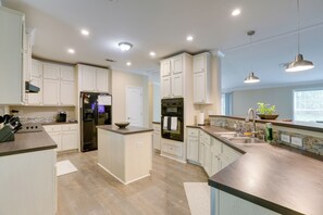 A modern kitchen with white cabinetry, stainless steel appliances, and pendant lighting.