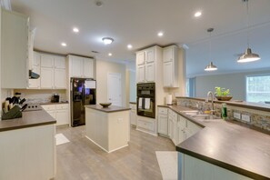 A modern kitchen with white cabinetry, a central island, stainless steel appliances, and pendant lighting.
