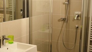 A bathroom with a white sink, a glass shower enclosure, and a mirror. - Appartment "hochwart" (Nals)