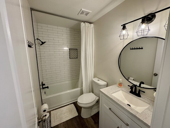 A modern bathroom with a glass-enclosed shower, a toilet, and a sink with a mirror.