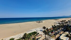 Una platja amb una zona d'aparcament i palmeres.