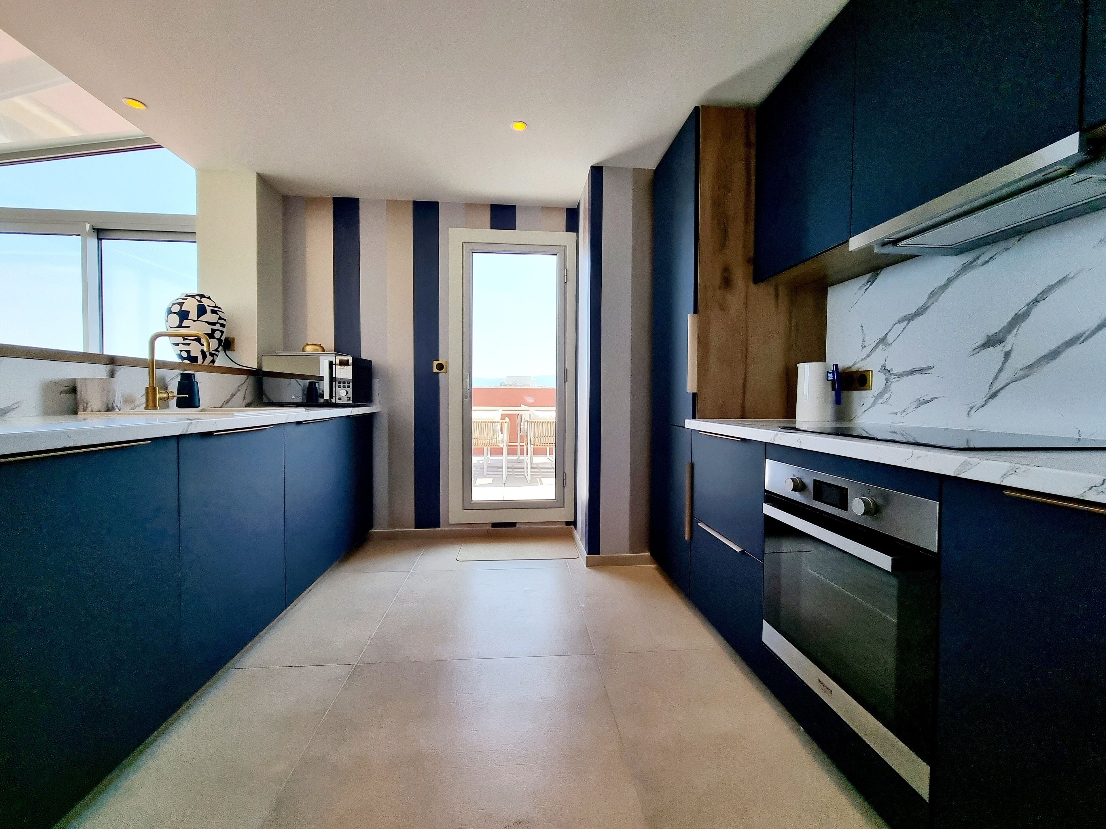 A modern kitchen with dark blue cabinets, a white countertop, and a large oven.