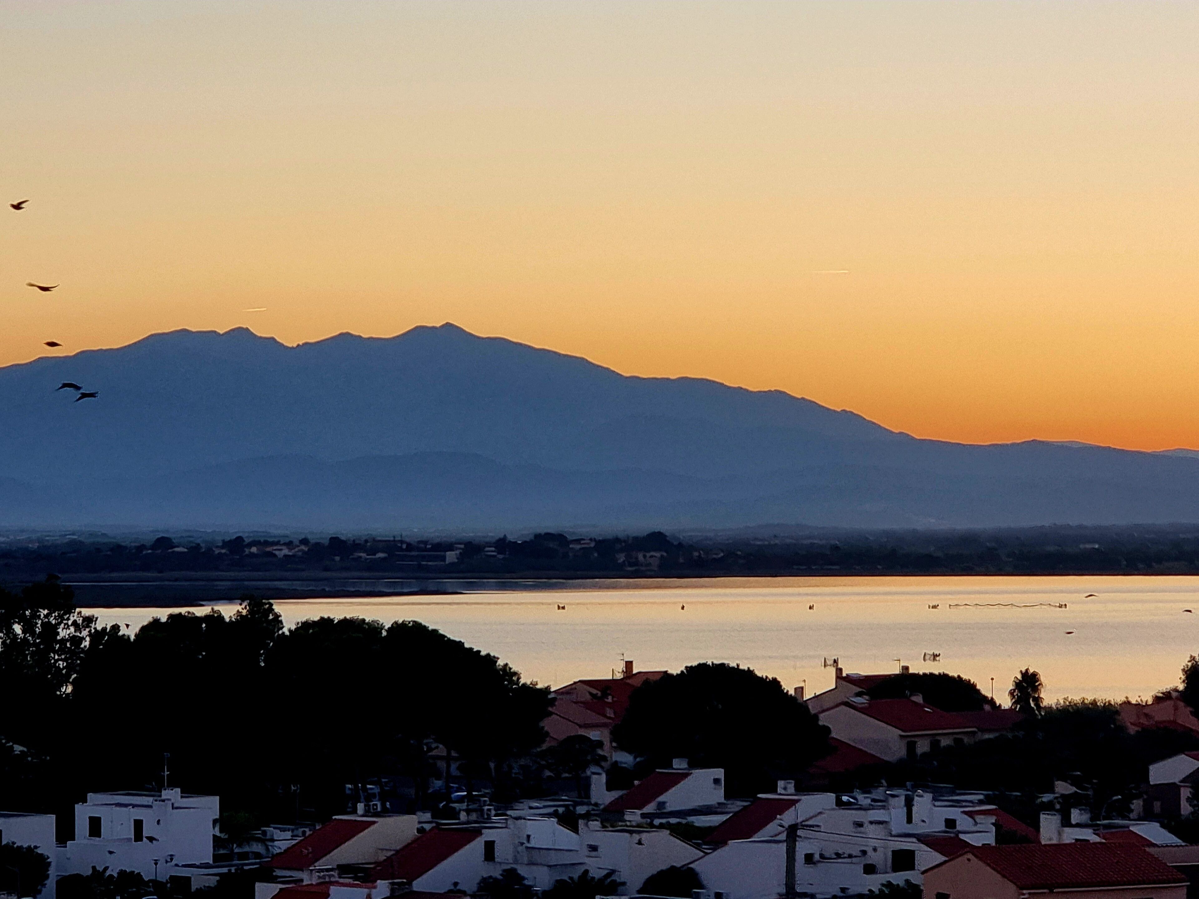 A coastal town with buildings in the foreground and mountains in the background.