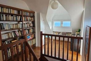Una habitación amplia con techo alto, una escalera de madera y una extensa colección de estanterías.