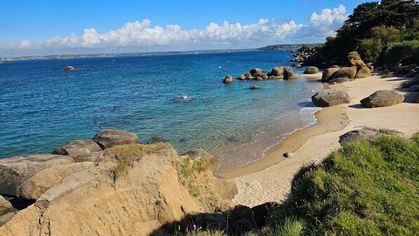 Eine Küstenlandschaft mit klarem, blauem Wasser, felsigem Ufer und einem Sandstrand.