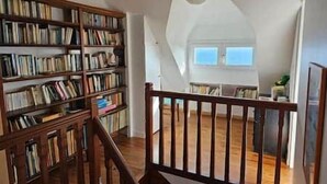 Una habitación amplia con techo alto, una escalera de madera y una extensa colección de estanterías.