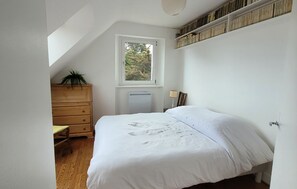 Ein Schlafzimmer mit einem Einzelbett, einem Holzschrank, einem Fenster und einem Deckenventilator.