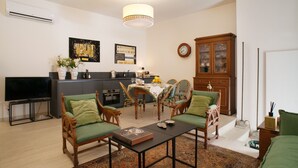 A living room with a dining area, a TV, and a kitchen in the background. - Via Giulia Charming Atelier apartment (Roma)