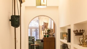A hallway with a lamp, a hanging bag, a sofa, and a bookshelf with decorative items. - Via Giulia Charming Atelier apartment (Roma)