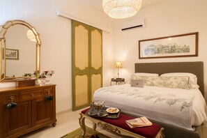 A hotel room with a bed, dresser, mirror, lamp, and a framed picture on the wall.