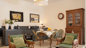 A living room with a dining area, a kitchen in the background, and a large wooden cabinet. - Via Giulia Charming Atelier apartment (Roma)