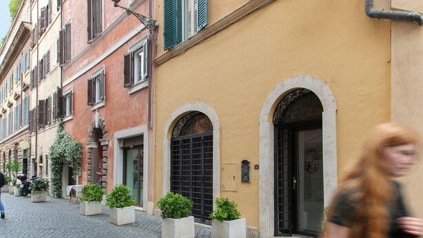 A cobblestone street with buildings featuring arched doorways and windows with shutters. - Via Giulia Charming Atelier apartment (Roma)