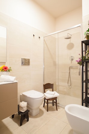 Un baño con inodoro, silla, ducha y bañera.