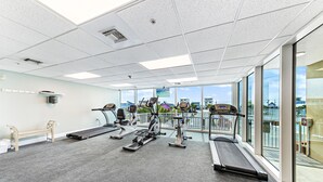 Une salle de sport équipée de tapis de course, de vélos elliptiques et d’un banc de musculation.