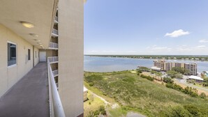 Un immeuble de grande hauteur doté de balcons donnant sur une étendue d’eau et sur un paysage lointain.