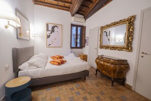 A bedroom with a bed, bedside table, dresser, and artwork on the walls. - Via Giulia Charming Apartment with Balcony (Roma)