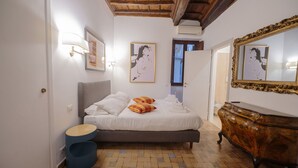 A bedroom with a bed, bedside lamps, a dresser, and artwork on the walls. - Via Giulia Charming Apartment with Balcony (Roma)