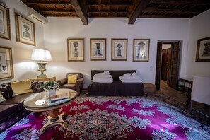 A room with a bed, a sofa, a table with a lamp, and framed pictures on the wall. - Via Giulia Charming Apartment with Balcony (Roma)