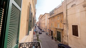 A narrow cobblestone street lined with historic buildings, a few parked cars, and a motorcycle. - Via Giulia Charming Apartment with Balcony (Roma)