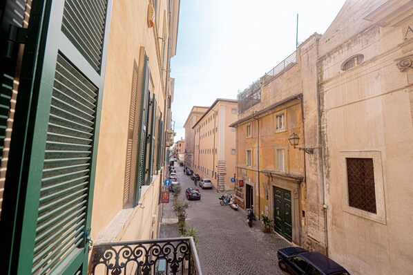 A narrow cobblestone street lined with historic buildings, a few parked cars, and a motorcycle. - Via Giulia Charming Apartment with Balcony (Roma)