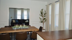 A dining area with a wooden table, chairs, a plant, and a sofa. - Welcome to Blue and Gold Getaway! (Morgantown)