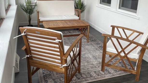 A cozy seating area with a wooden bench, a wooden table, and two chairs. There is a large window with a view of buildings and a railing outside. - Welcome to Blue and Gold Getaway! (Morgantown)