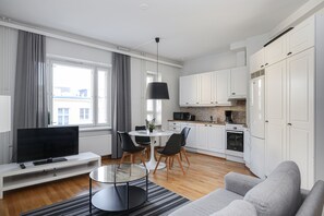 Un salon moderne avec un téléviseur à écran plat, une table basse en verre et un canapé gris.