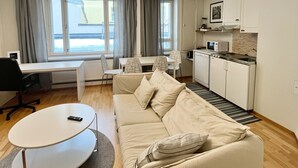 Ein modernes Wohnzimmer mit einer Couch, einem Esstisch und einer Küchenzeile.