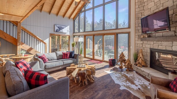 A spacious living area with a stone fireplace, large windows, and a cozy seating arrangement. - White Tail Lodge by Innsbrook Vacations! (Innsbrook)