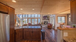 A spacious kitchen with wooden cabinets, a granite countertop, and a stone fireplace. - White Tail Lodge by Innsbrook Vacations! (Innsbrook)