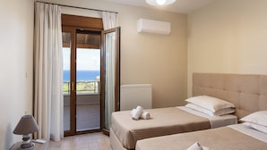 A hotel room with two beds, a view of the sea, a ceiling fan, and a window with curtains. - Villa Aris: A Serene Experience, 3BRs, Pool & Bbq (Rethymno)