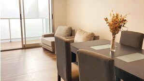 Een moderne woonkamer met een eettafel, een bank en een vaas met gedroogde bloemen.