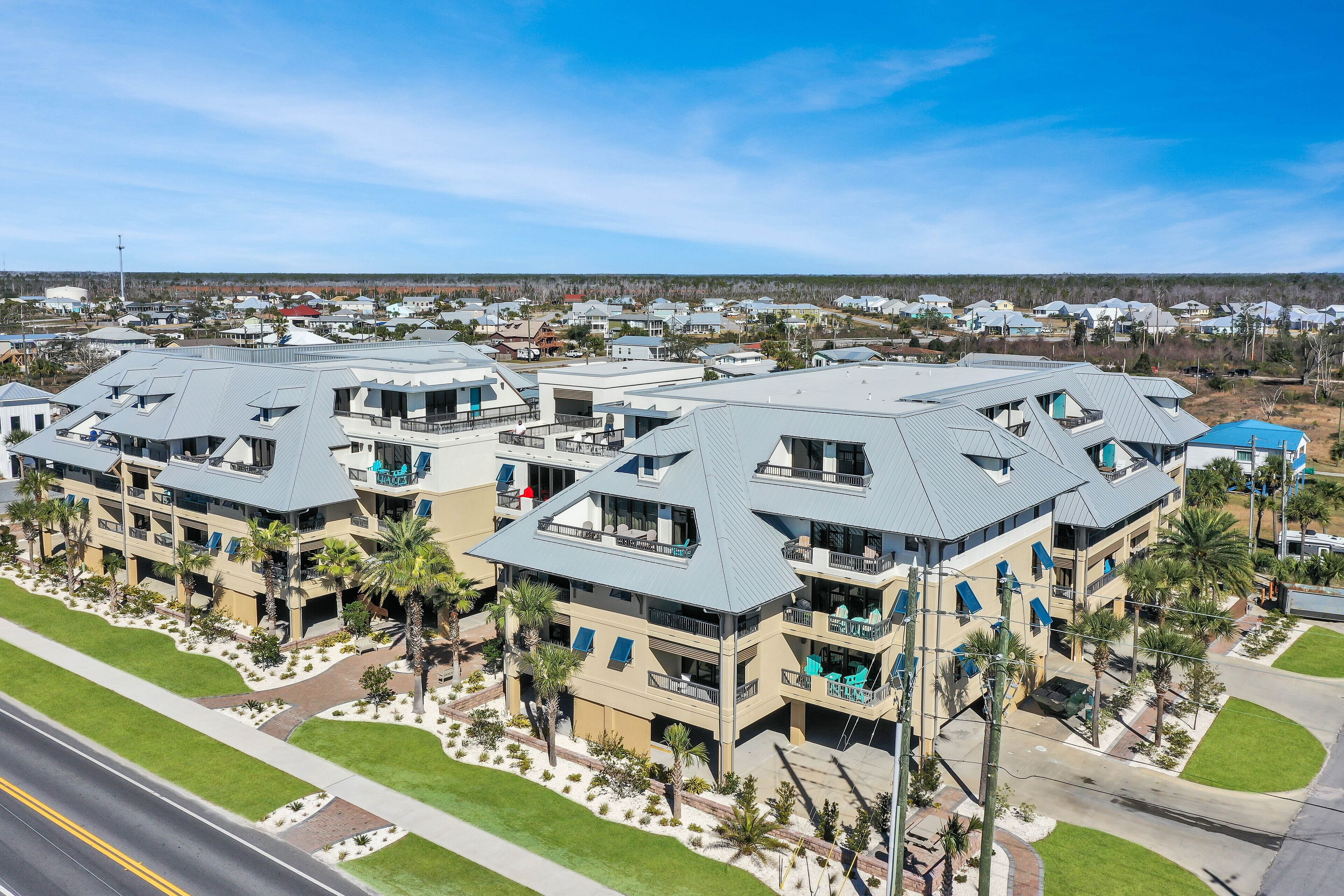 A multi-story hotel with balconies, a parking area, and a well-maintained lawn.
