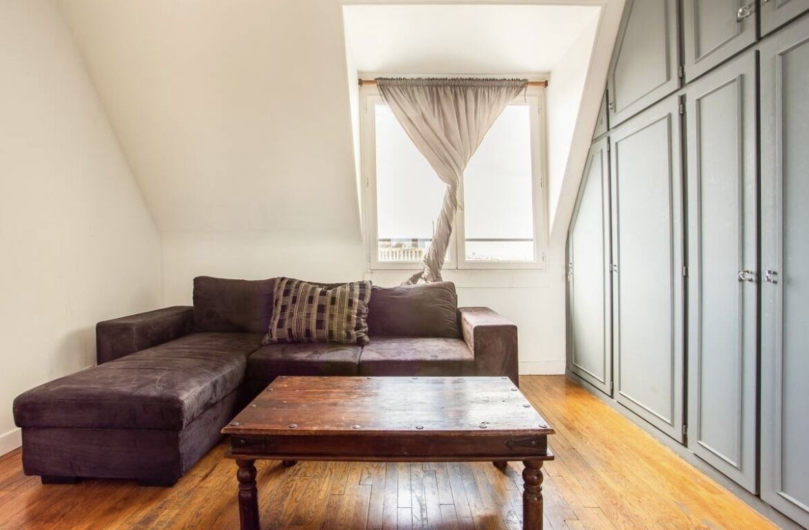Una habitación con un sofá modular, una mesa de centro de madera y una ventana con cortinas.